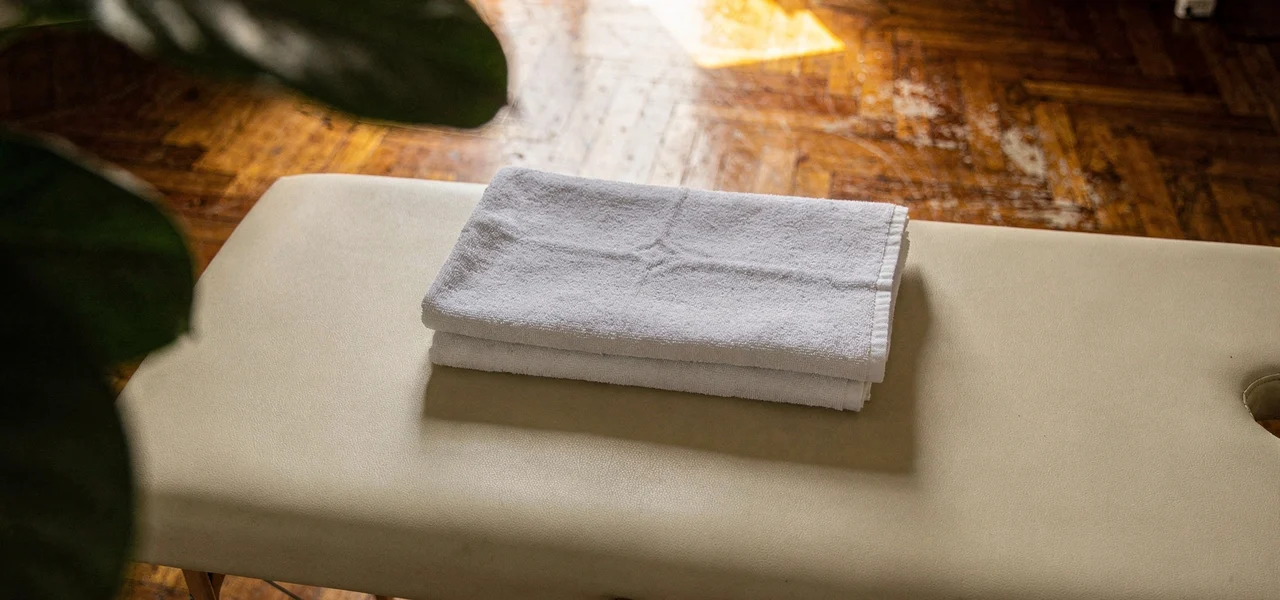 Table de massage dépliée dans un salon, serviettes blanches pliées posées dessus